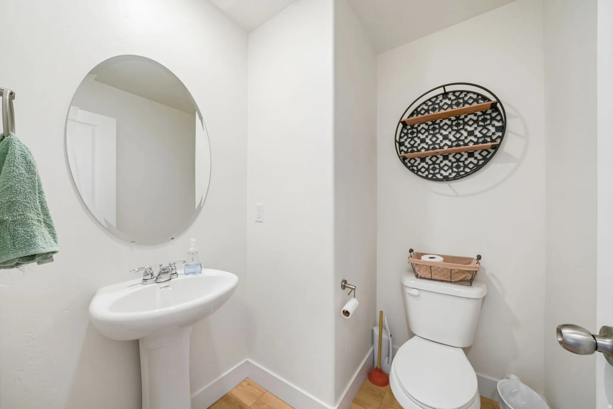 Pedestal sink with chrome fixtures and an oval mirror