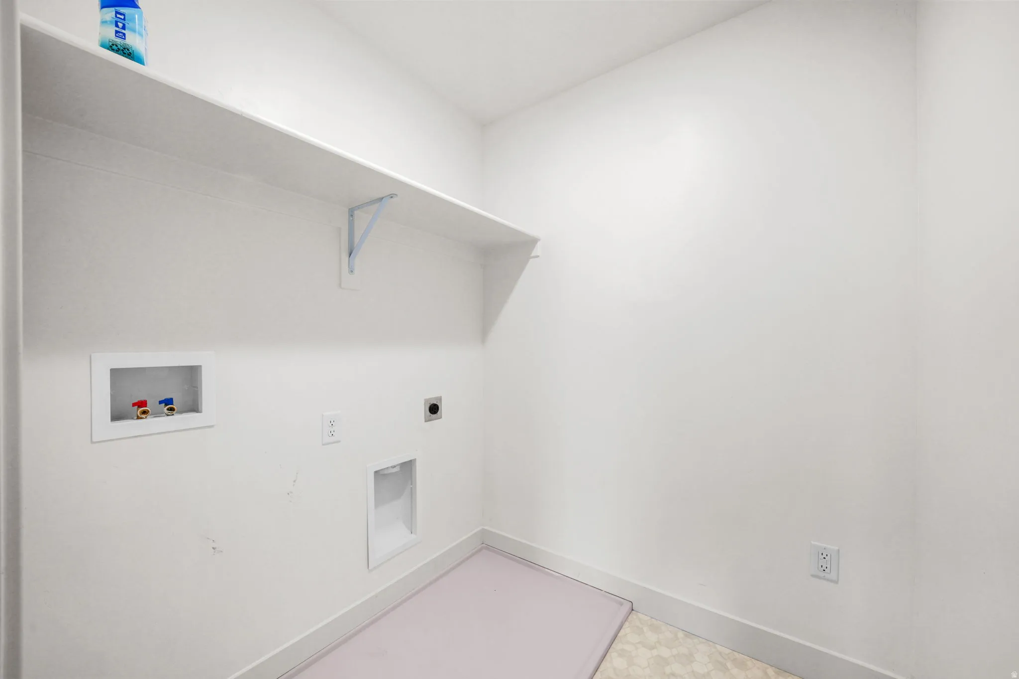 Dedicated laundry area featuring a built-in white shelf, water hookups, and electrical outlets