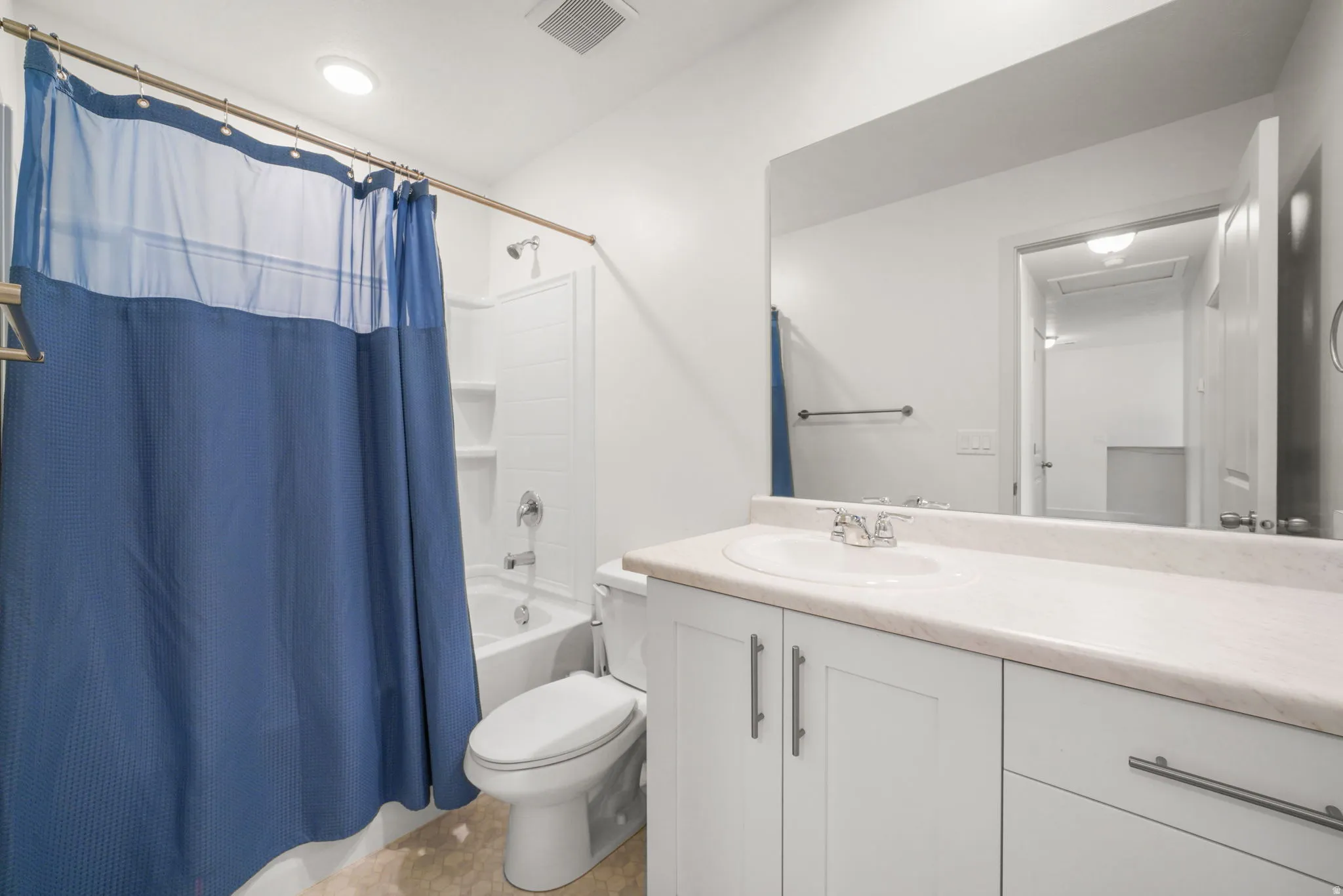 Bathroom featuring a white vanity with an integrated sink, polished chrome faucet, and white cabinetry