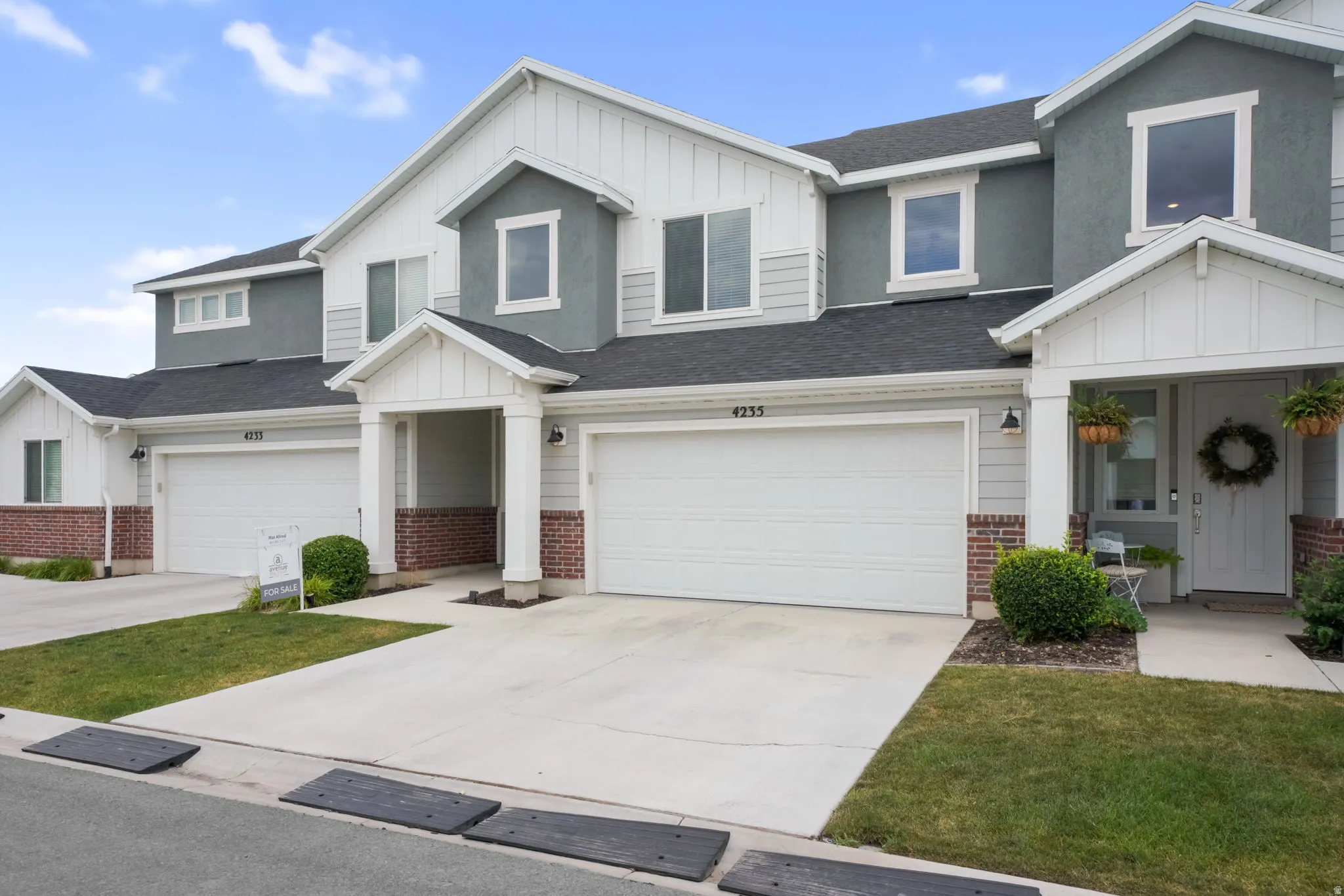 Modern townhome exterior featuring multi-toned siding, dark shingle roofing, and red brick accents