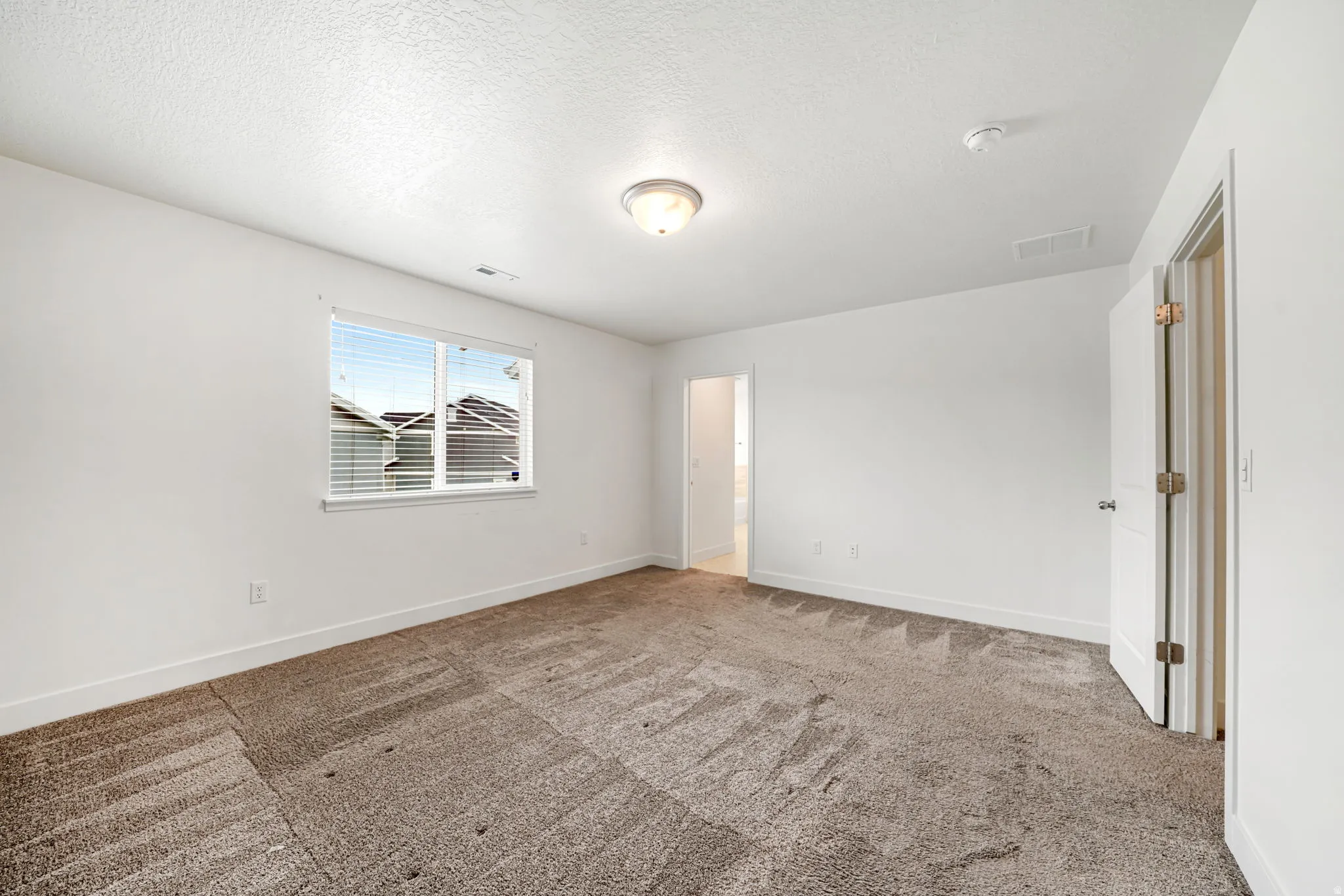 Spacious room featuring neutral carpeting and white walls