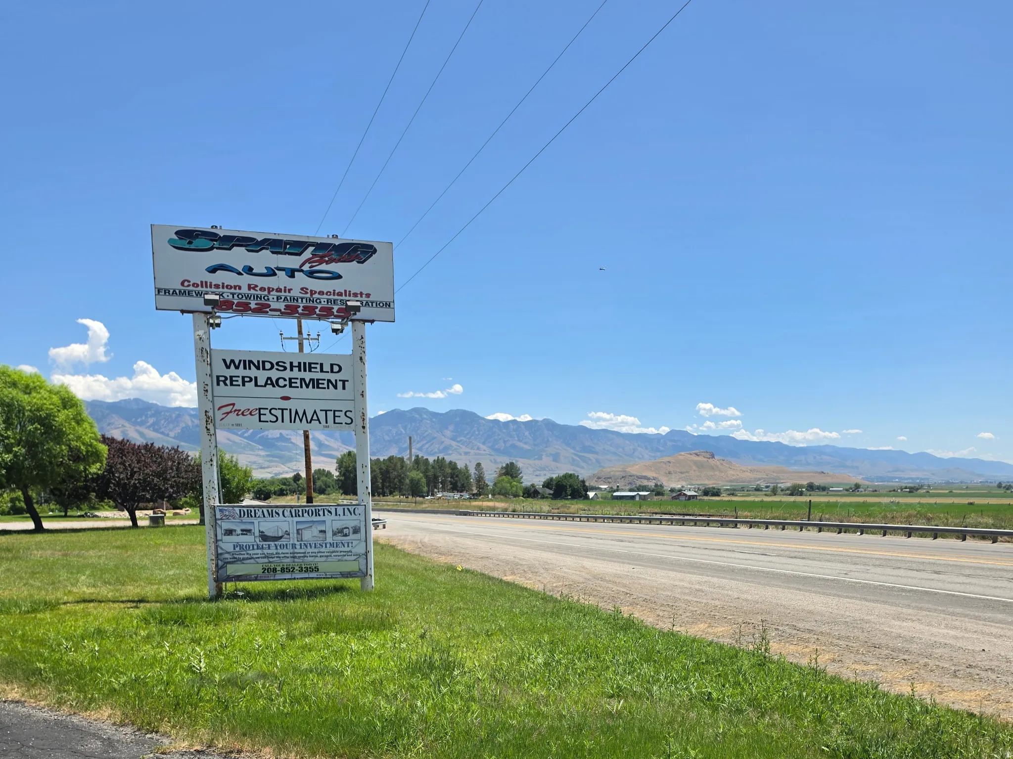 Roadside signage with multiple business advertisements, set against a backdrop of distant mountains