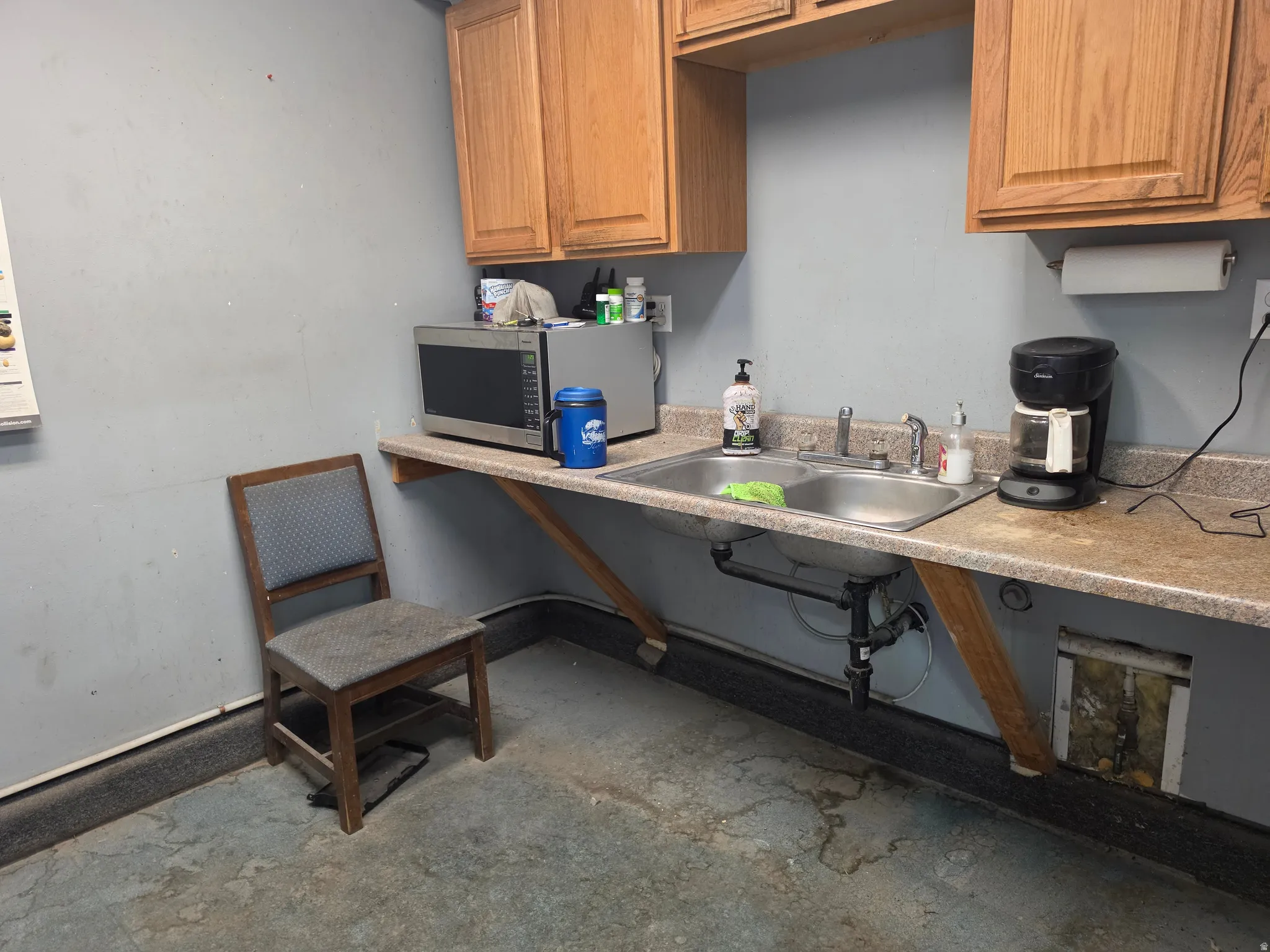 Utility area featuring a double basin stainless steel sink, laminate countertops, and wood cabinetry