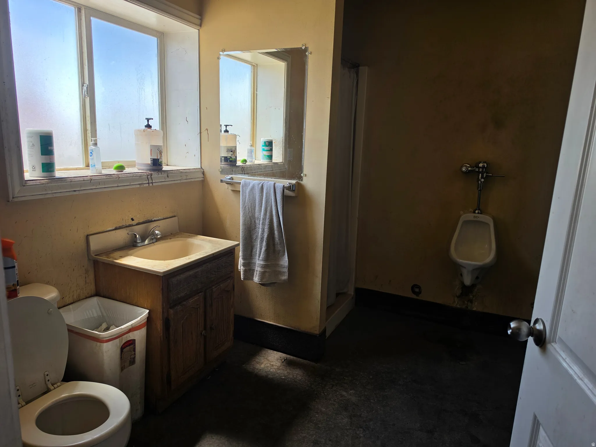 Bathroom featuring a single window, a vanity with an integrated sink, a wall-mounted mirror, a commode,  urinal and shower.