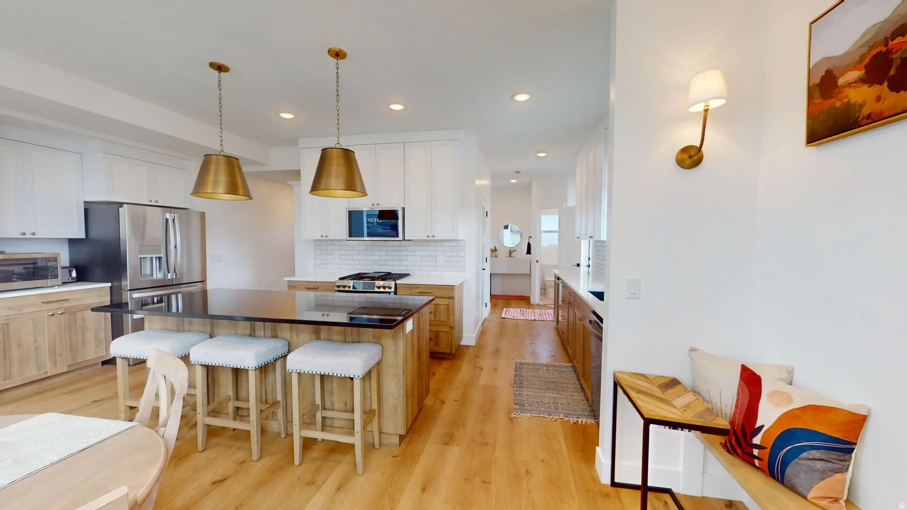 Contemporary kitchen featuring a large island with dark countertop, stainless steel appliances, white subway tile backsplash, and wood-finish flooring