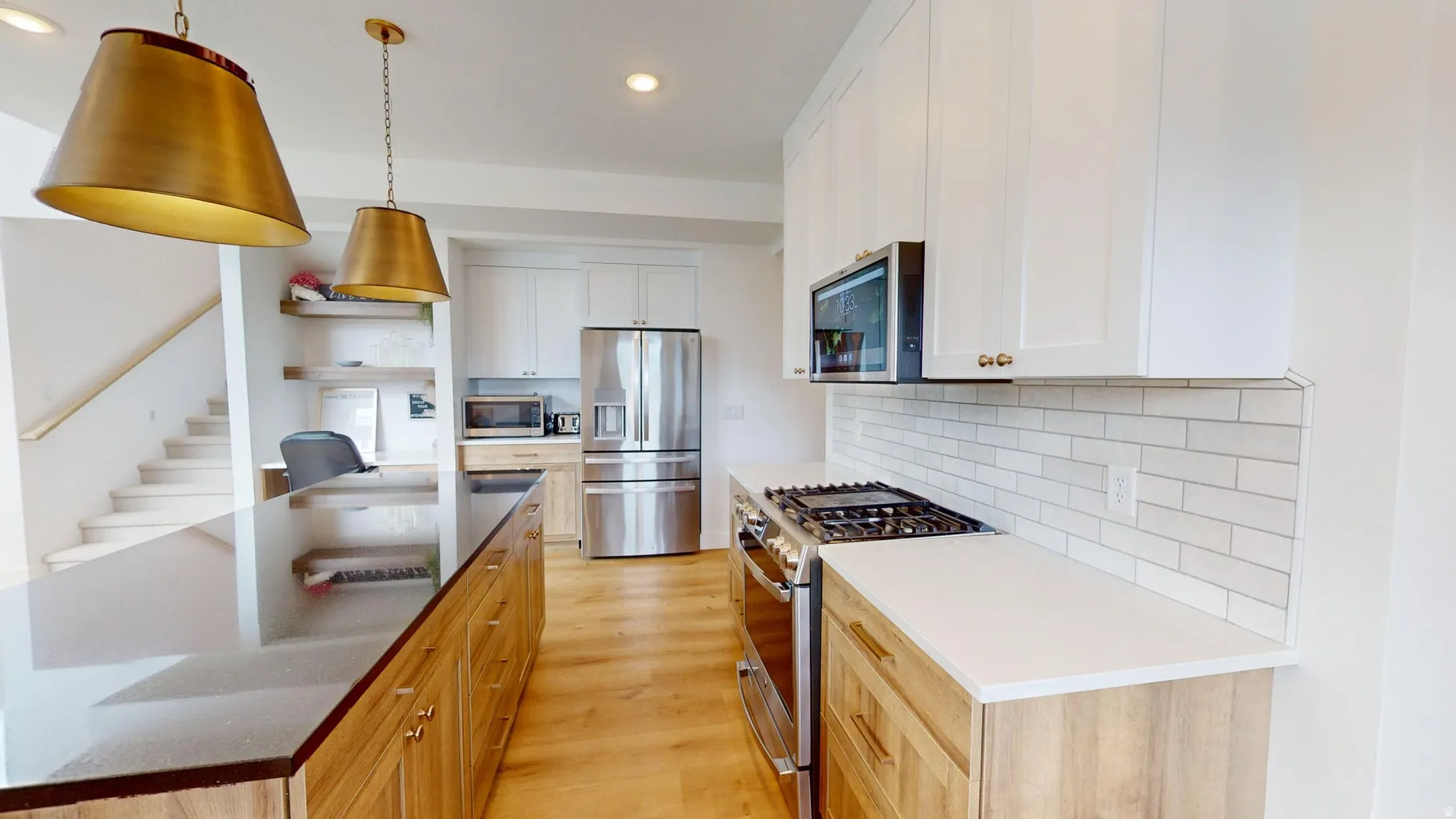 Bright kitchen featuring white upper cabinetry, wood-finish lower cabinetry, and stainless steel appliances