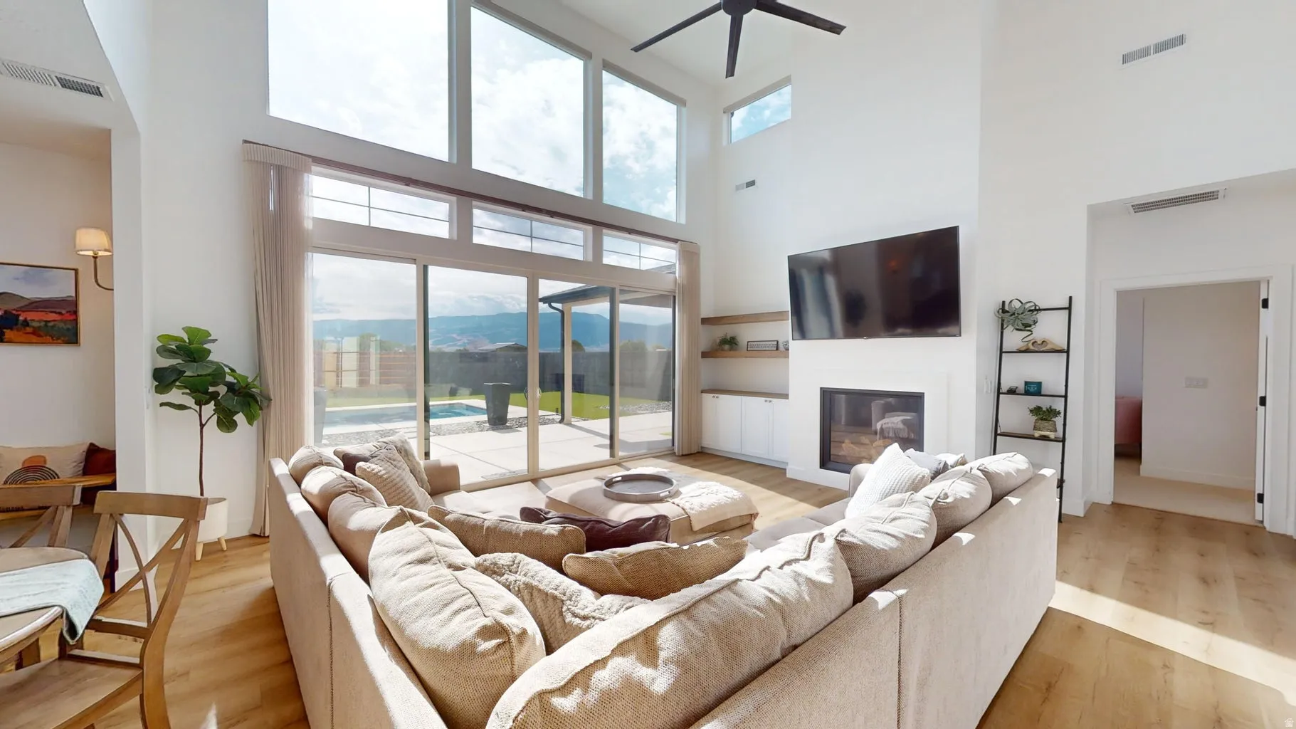 Vaulted ceilings highlight a modern living space featuring a fireplace, integrated shelving, and wood-finish flooring