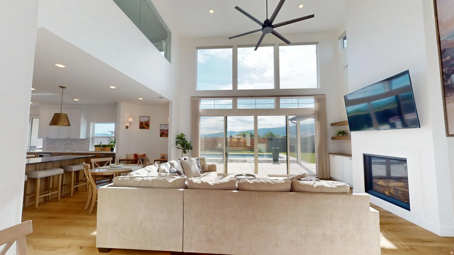 Two-story living area with high ceilings, wood-finish flooring, and a contemporary ceiling fan