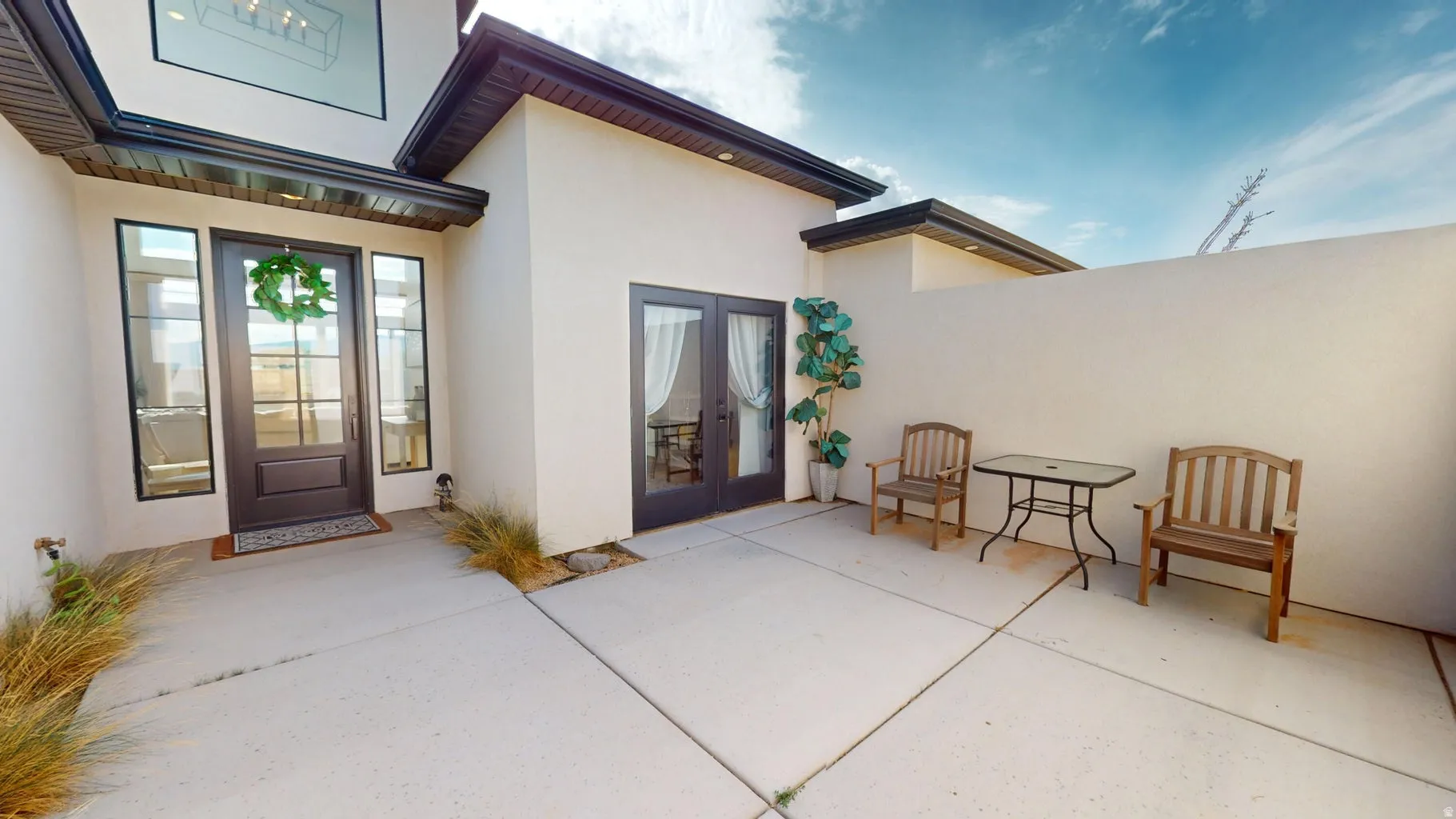 Private courtyard featuring concrete paving, a tall perimeter wall, and architectural planting beds