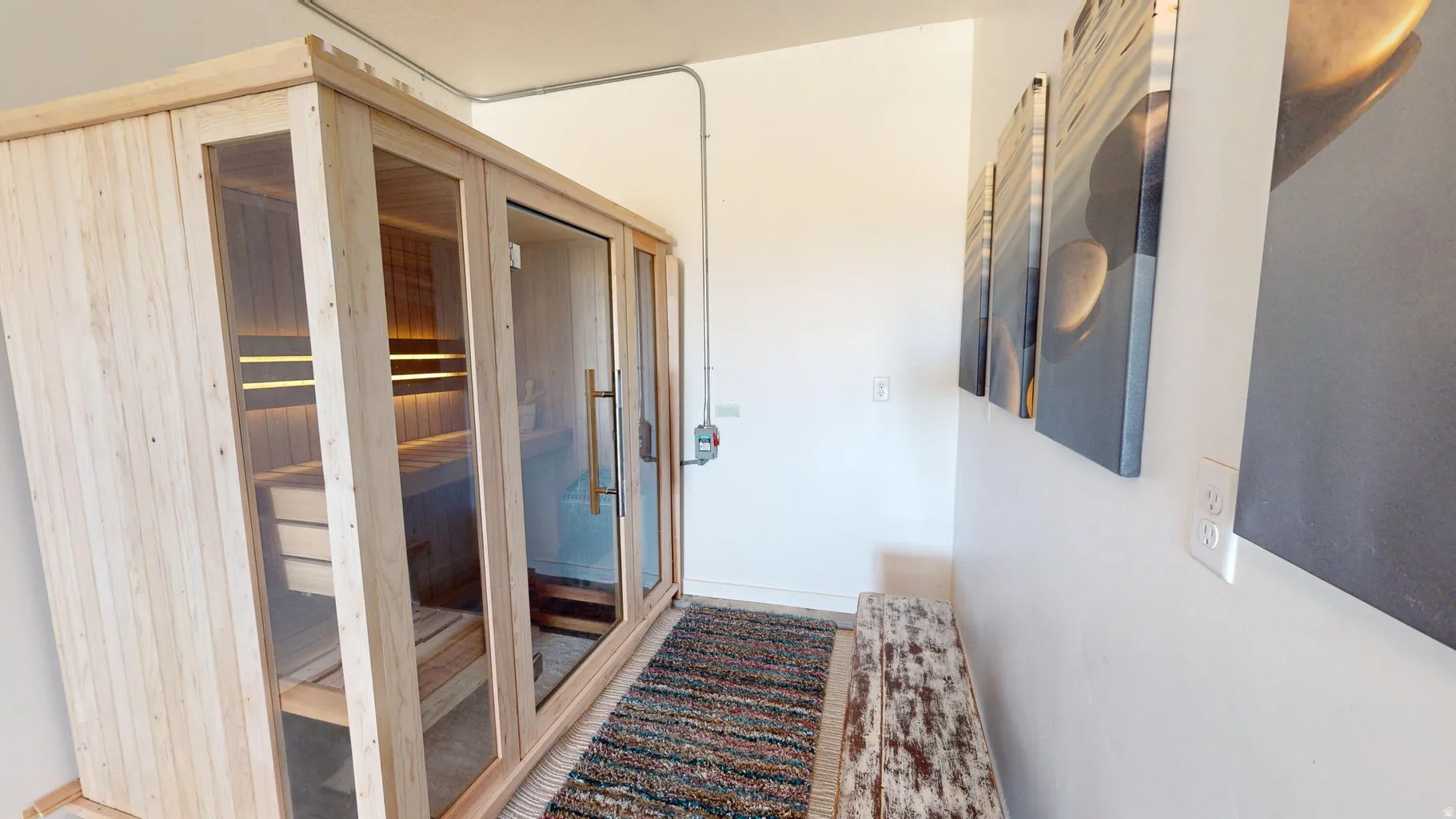 Freestanding sauna unit featuring light wood paneling, glass doors, and interior bench seating