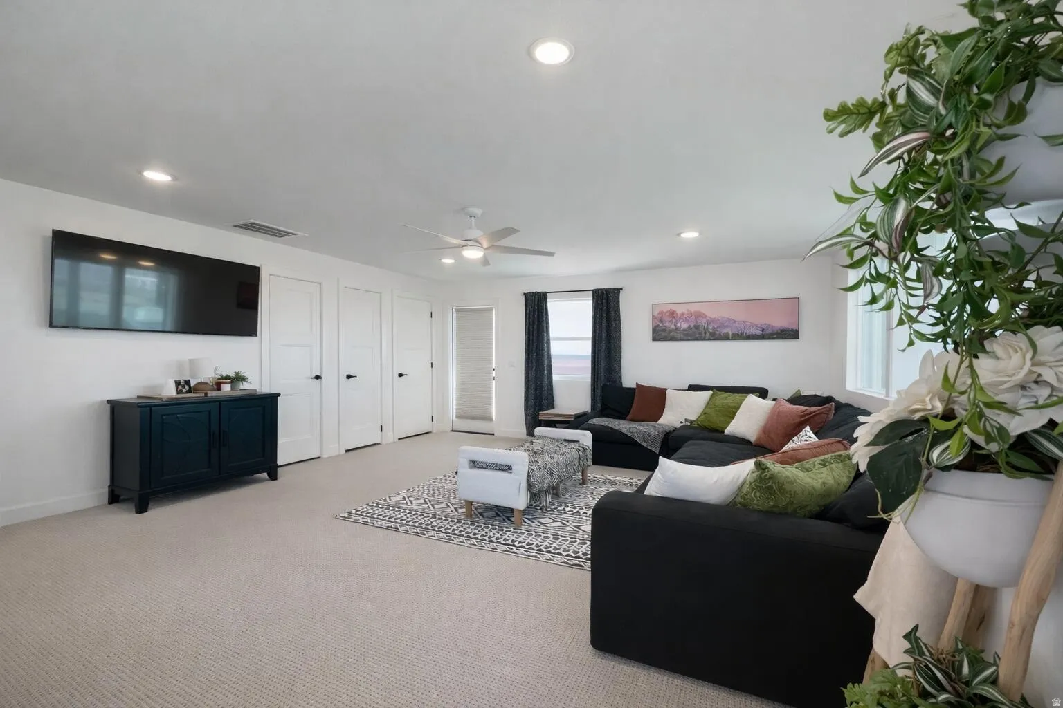 Spacious entertainment area with neutral carpeting and recessed lighting
