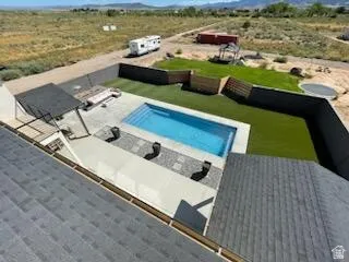 Rear exterior featuring an in-ground swimming pool, concrete patio, artificial turf lawn, and a covered pergola