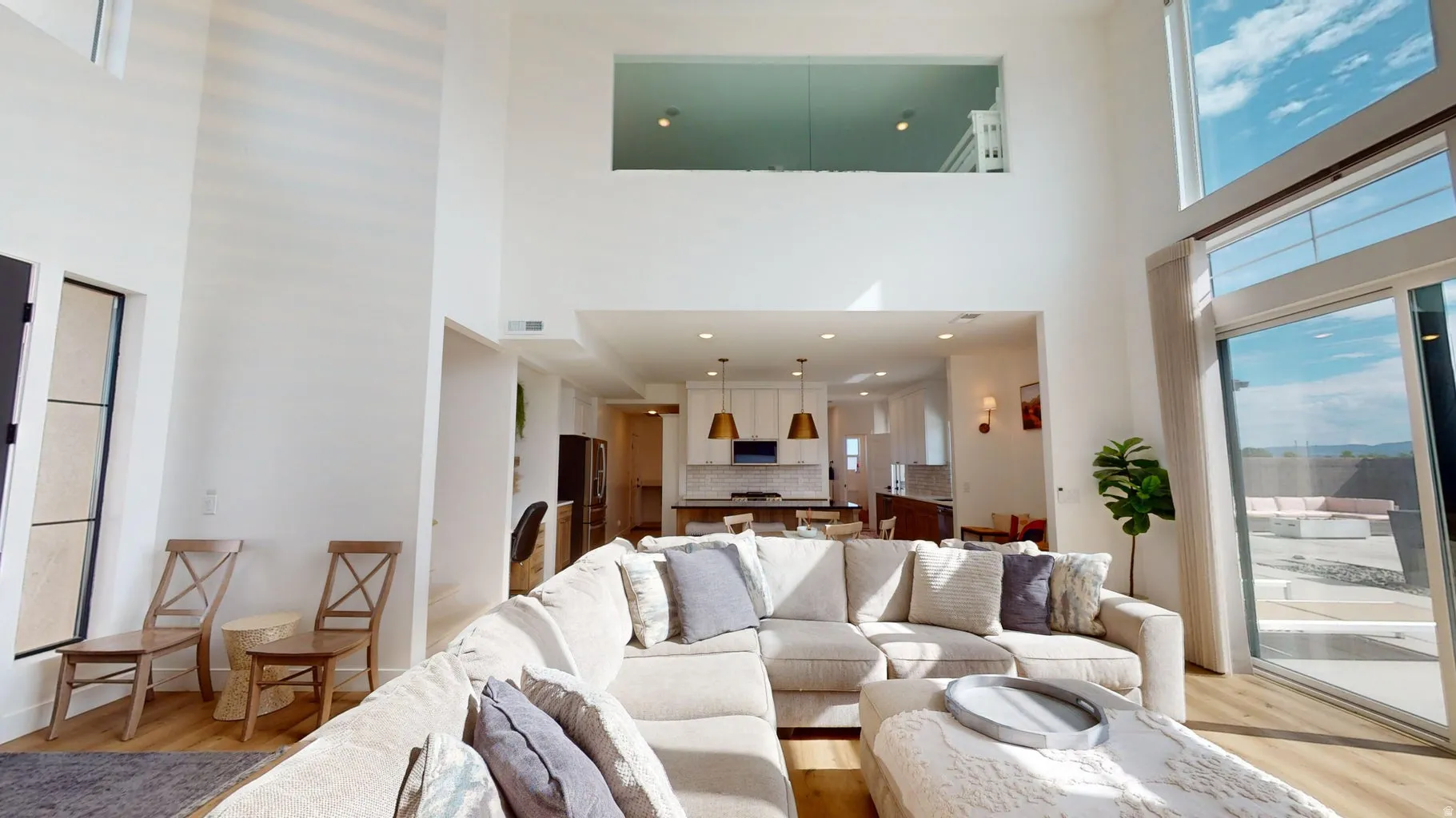 Vaulted living space featuring high ceilings, tall windows, and wood-finish flooring