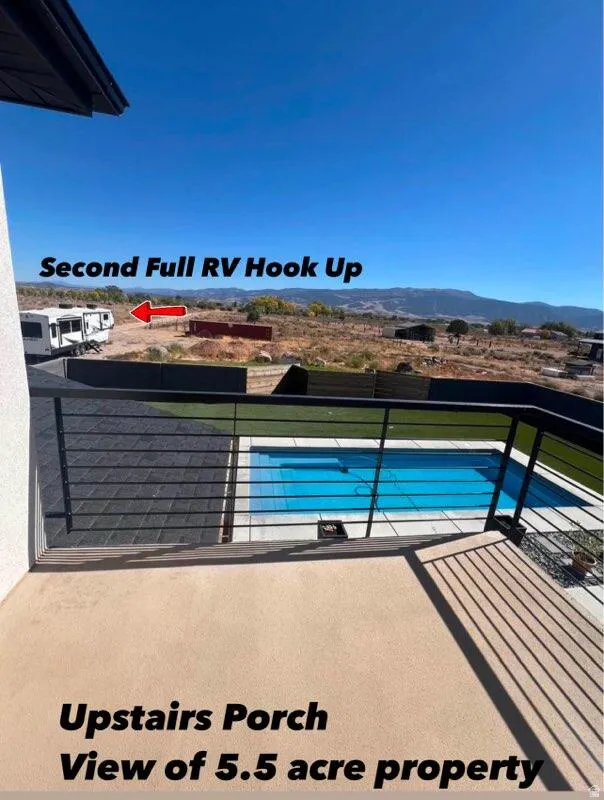 Expansive outdoor living area featuring a rectangular pool, a spacious patio, and a metal railing