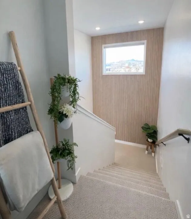 Carpeted staircase featuring a light wood accent wall, recessed lighting, and a window providing natural illumination