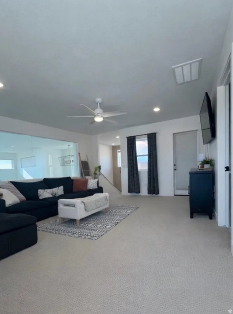 Spacious room featuring light-toned carpeting, recessed lighting, and a ceiling fan