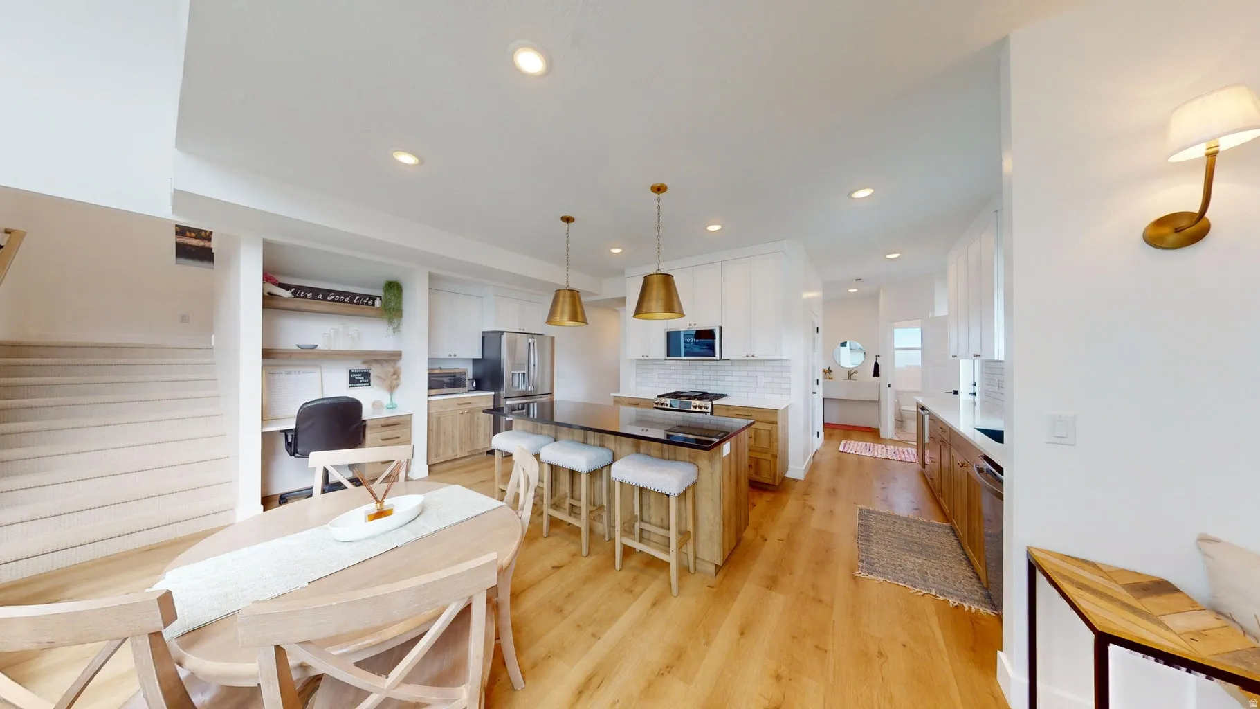 Open-concept kitchen and dining area featuring wood-finish flooring, recessed lighting, and a kitchen island with seating