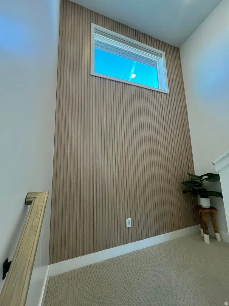 Accent wall featuring vertical wood-finish paneling and a high transom window
