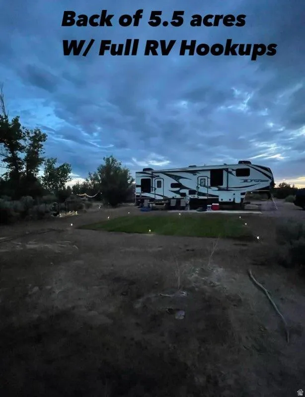 RV hookups present on a spacious lot, featuring a manicured grass patch and surrounding natural landscaping