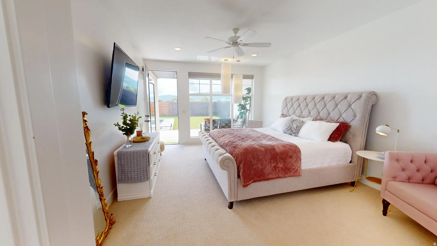 Spacious bedroom featuring light-colored carpet, white walls, and a ceiling fan