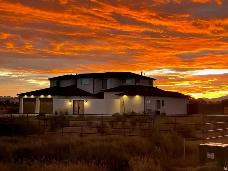 Contemporary stucco exterior featuring a tiered roofline, an attached two-car garage with modern doors, and a double entry door with sconce lighting
