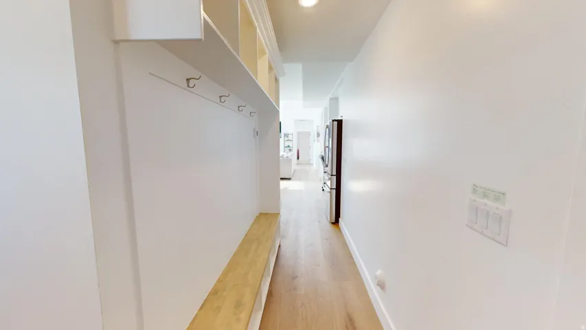 Entryway featuring built-in bench seating with storage, coat hooks, and overhead cubbies