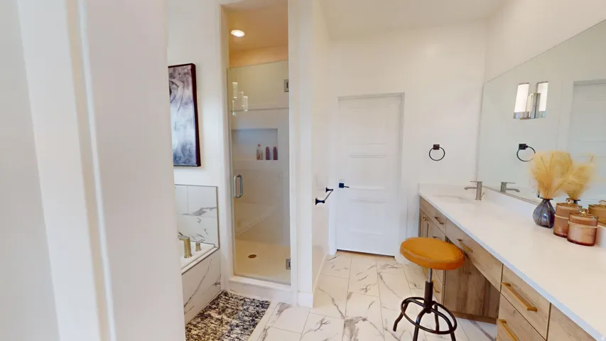 Expansive bathroom featuring a walk-in shower with glass enclosure, a built-in soaking tub with a tiled surround, a lengthy vanity with dual sinks, and large-format porcelain tile flooring