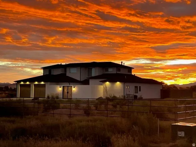 Contemporary stucco exterior featuring a tiered roofline, an attached two-car garage with modern doors, and a double entry door with sconce lighting