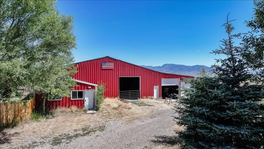 Red metal barn structure featuring multiple large bay openings and a separate side entrance