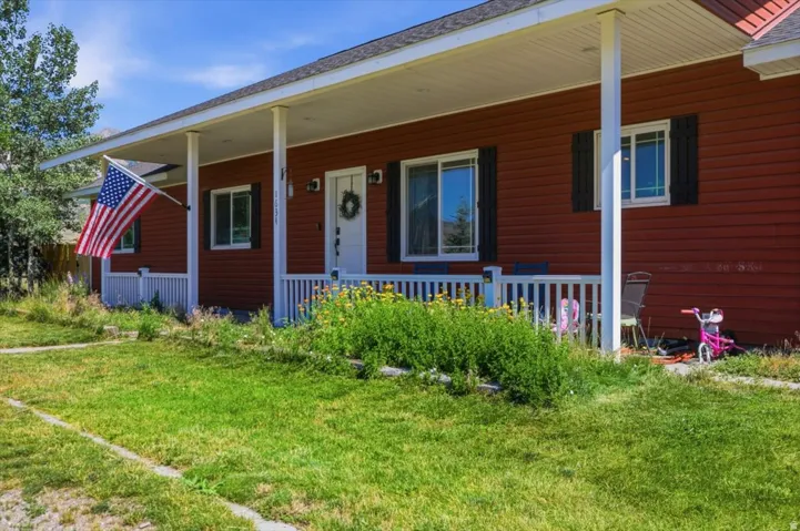 Red siding exterior featuring a covered front porch with white railing