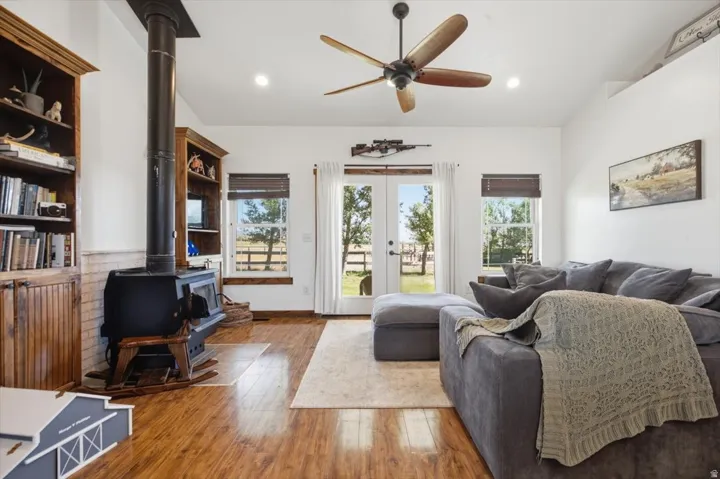 Living area featuring wood-finish flooring, a freestanding wood-burning stove, built-in wooden shelving, vaulted ceilings, and French doors opening to outdoor space