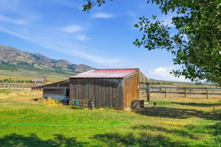 Rustic barn with red metal roof, weathered wood siding, and adjacent fenced pastures