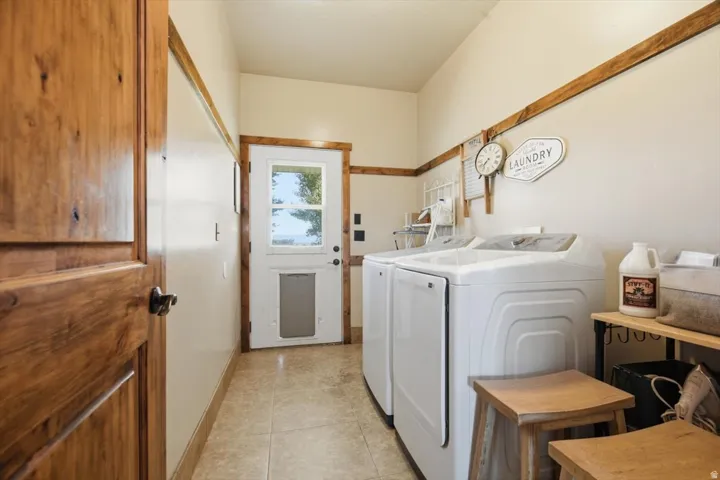 Laundry area featuring wood-finish trim, neutral wall tones, and tiled flooring