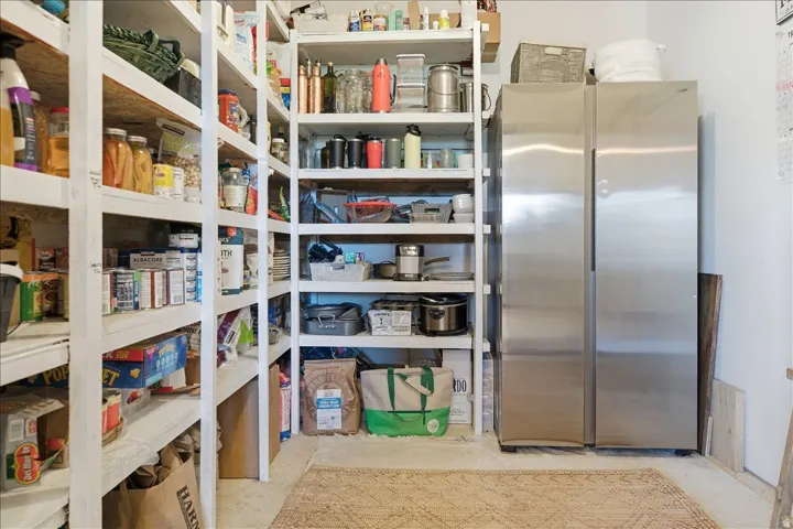 Custom pantry featuring extensive open shelving, two full-height stainless steel refrigerators, and durable flooring