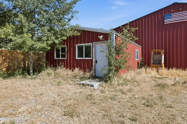 Red corrugated metal exterior featuring white trim windows and a white entry door