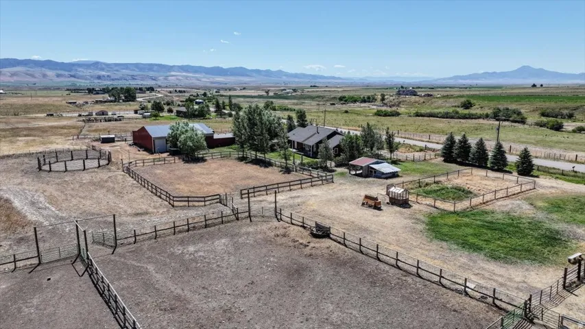 Expansive rural property featuring multiple fenced paddocks, a circular pen, and a large red barn with a silver roof