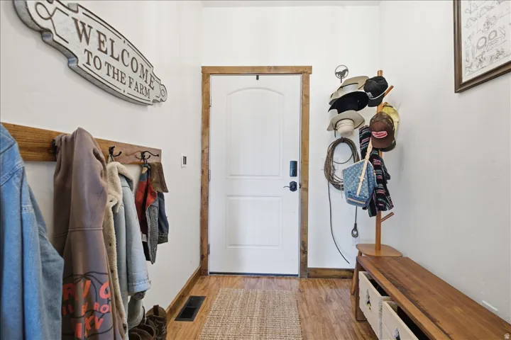 Entryway featuring a white paneled door with dark hardware, natural wood-finish trim, and wood-finish flooring