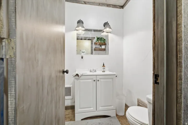 Bathroom featuring a white vanity with integrated sink, dual wall-mounted sconces, and corrugated metal ceiling detail