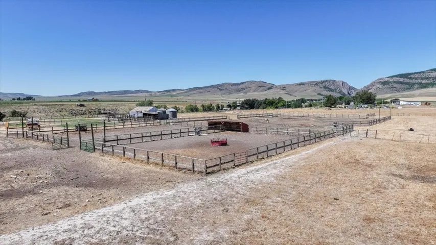 Extensive fenced paddocks and corrals with multiple gates, a barn structure, and two grain silos