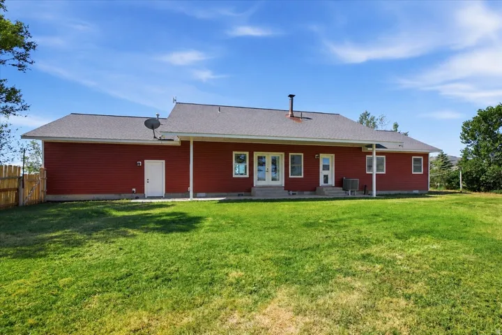 Spacious backyard featuring a manicured lawn, a red siding exterior, and a white fence