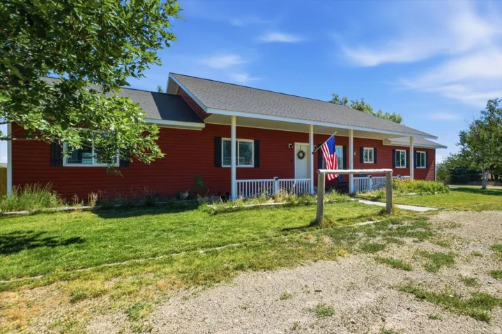 Red siding exterior with a covered front porch featuring white railings and columns