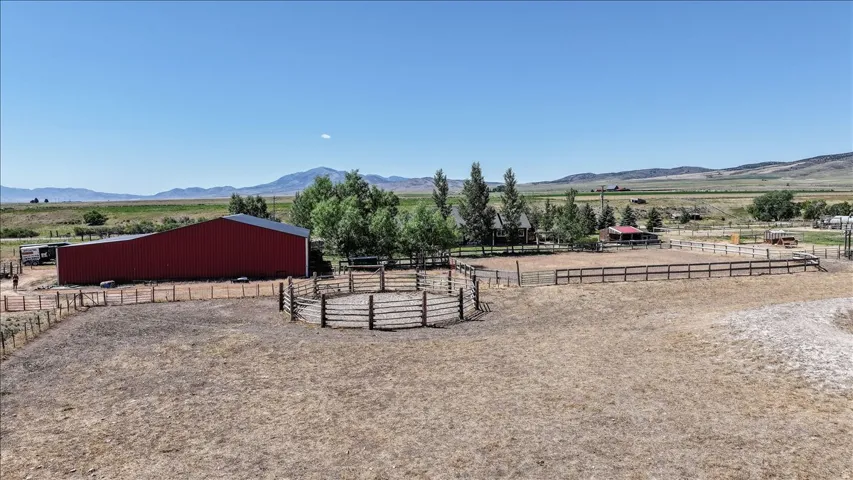 Expansive property featuring a large red barn with a metal roof, a round pen, and a rectangular fenced riding arena