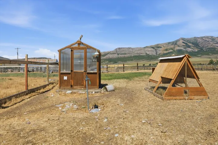 Wood-framed greenhouse featuring clear paneling and a dedicated water spigot