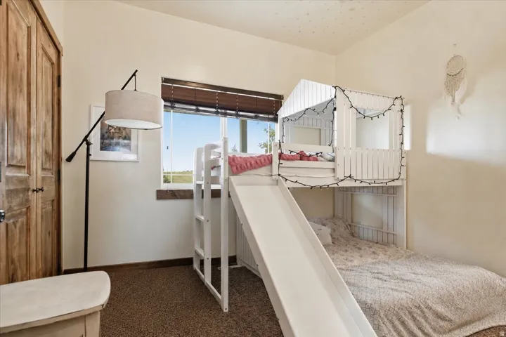 Bright room featuring wood-finish bi-fold closet doors, a wide window with wood blinds, and wall-to-wall carpeting