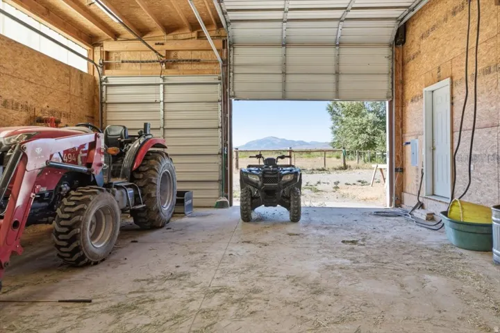 Spacious garage interior featuring concrete flooring, exposed wood framing, and two large overhead doors