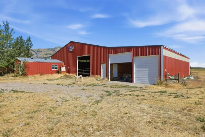 Expansive red metal barn structure with multiple bay doors and an attached smaller red metal outbuilding