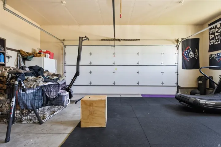 Garage space featuring a roll-up garage door, painted walls, overhead lighting, and a partial rubber flooring system