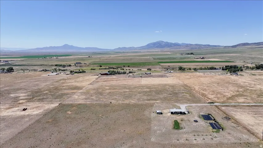 Expansive rural property featuring a single-story dwelling, outbuildings, and agricultural plots