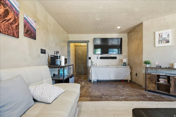 Distressed concrete flooring complements textured wall finishes and a built-in entertainment area