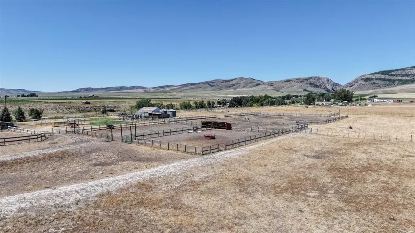 Expansive outdoor property with multiple fenced enclosures and a distant agricultural building